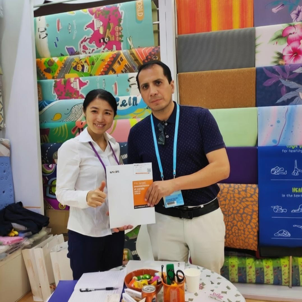 Uwin representative presenting custom mat samples to an international trade show buyer