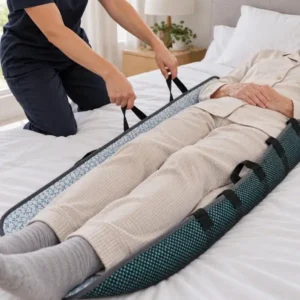Caregiver using a positioning bed pad with handles to assist an older adult lying on a bed.